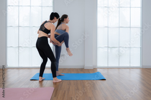 Young woman practicing yoga with instructor in house. Individual yoga class practicing in house
