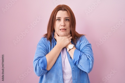 Young hispanic woman with red hair standing over pink background shouting suffocate because painful strangle. health problem. asphyxiate and suicide concept.