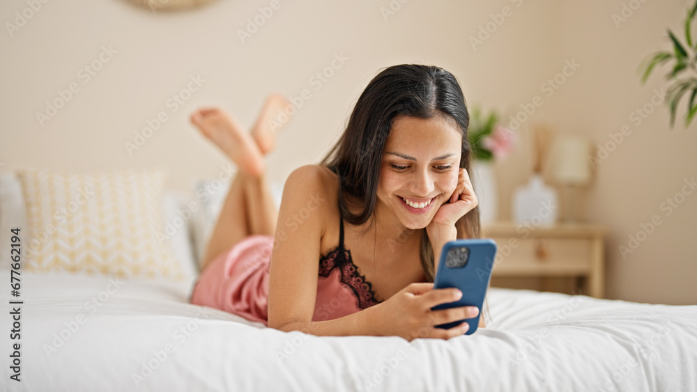 Young beautiful hispanic woman using smartphone lying on bed at bedroom Young beautiful hispanic woman using smartphone lying on bed at bedroom