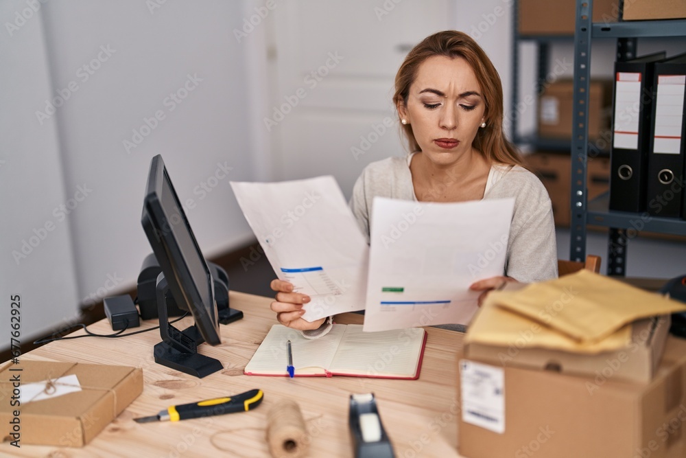 Young woman ecommerce busines worker reading document working at office Young woman ecommerce busines worker reading document working at office