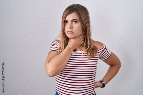 Young hispanic woman standing over isolated background touching painful neck, sore throat for flu, clod and infection