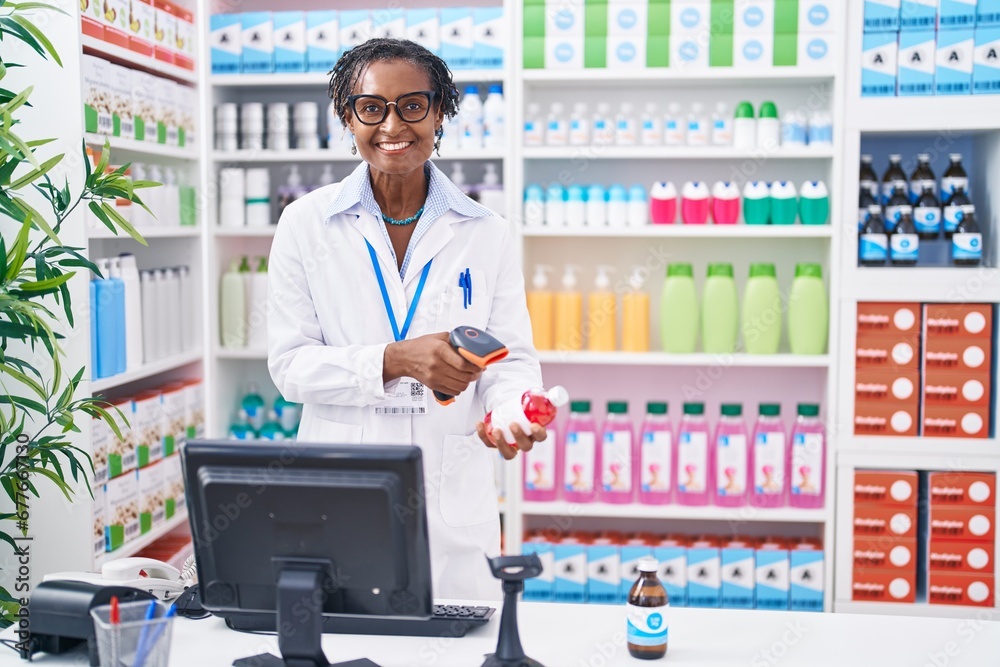 Middle age african american woman pharmacist scanning pills bottle at pharmacy