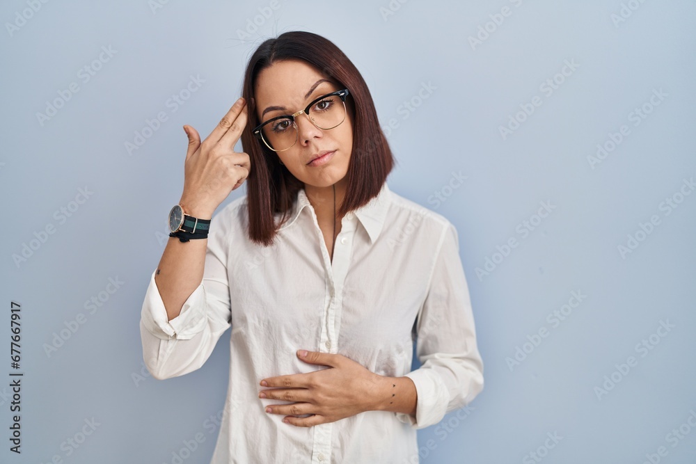 Young hispanic woman standing over white background shooting and killing oneself pointing hand and fingers to head like gun, suicide gesture.