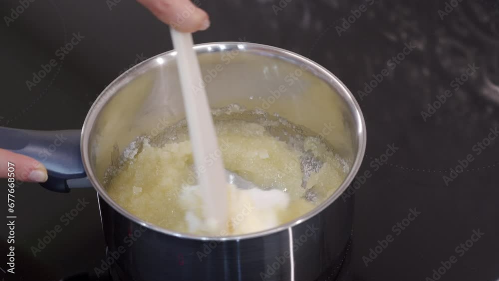 woman melts butter with sugar in saucepan on the stove for cooking Christmas gingerbread cookies woman melts butter with sugar in saucepan on the stove for cooking Christmas gingerbread cookies