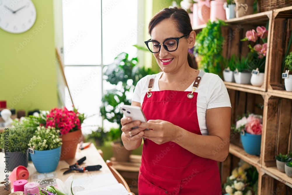 Young beautiful hispanic woman florist smiling confident using smartphone at flower shop