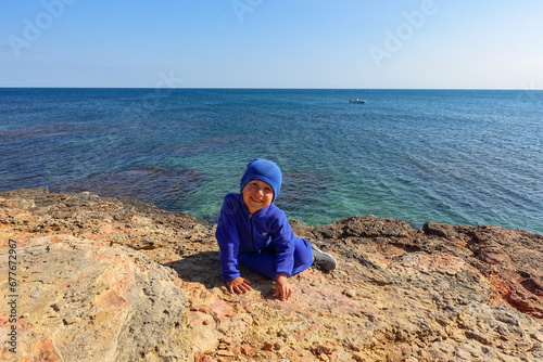 A boy on Cape Tarkhankut. The rocky coast of the Dzhangul Reserve in the Crimea. Turquoise sea water. Rocks and grottoes of Cape Tarkhankut on the Crimean Peninsula