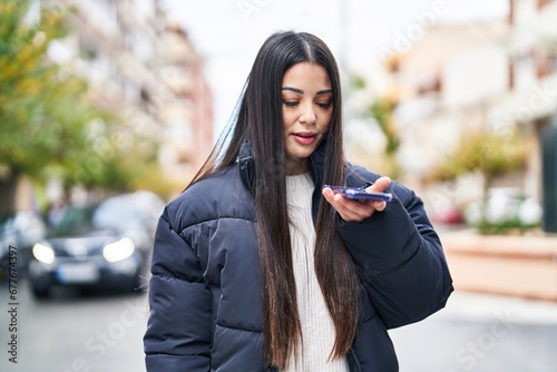Young beautiful hispanic woman talking on smartphone with relaxed expression at street