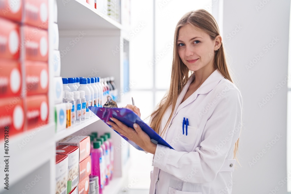 Young caucasian woman pharmacist writing on document at pharmacy