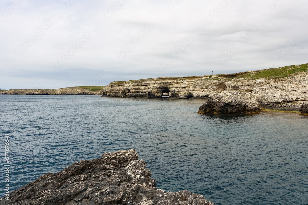 Cape Tarkhankut on the Crimean peninsula. The rocky coast of the Dzhangul Reserve in the Crimea. The Black Sea. Turquoise sea water. Rocks and grottoes of Cape Tarkhankut. Cape Tarkhankut on the Crimean peninsula. The rocky coast of the Dzhangul Reserve in the Crimea. The Black Sea. Turquoise sea water. Rocks and grottoes of Cape Tarkhankut.