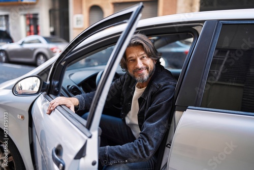 Middle age man smiling confident opening car door at street © Krakenimages.com