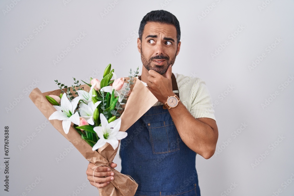 Hispanic man with beard working as florist thinking worried about a question, concerned and nervous with hand on chin Hispanic man with beard working as florist thinking worried about a question, concerned and nervous with hand on chin
