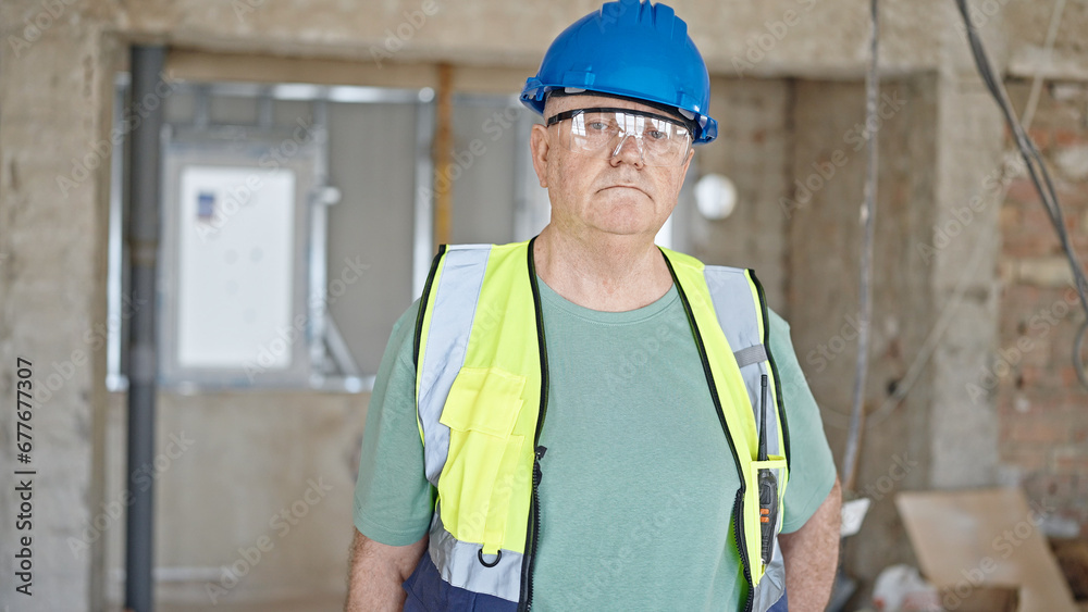 Middle age grey-haired man builder standing with relaxed expression at construction site Middle age grey-haired man builder standing with relaxed expression at construction site