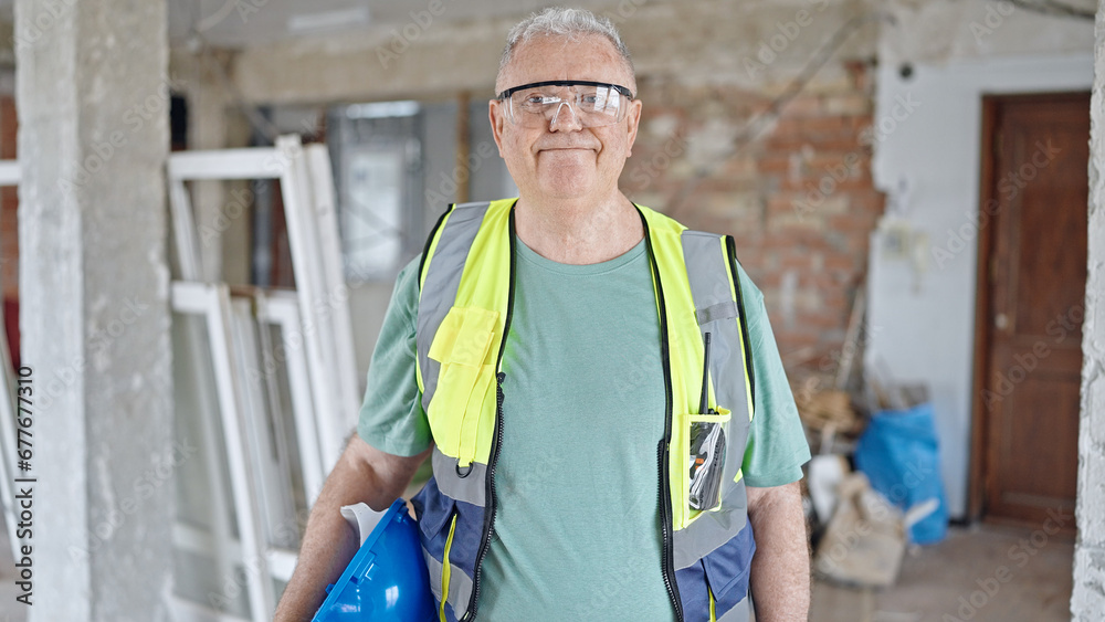 Middle age grey-haired man builder smiling confident holding hardhat at construction site Middle age grey-haired man builder smiling confident holding hardhat at construction site