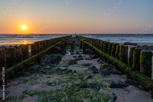 During low tide, the setting sun shines beautifully on the algae-covered pile heads on both sides of the breakwater at Westkapelle