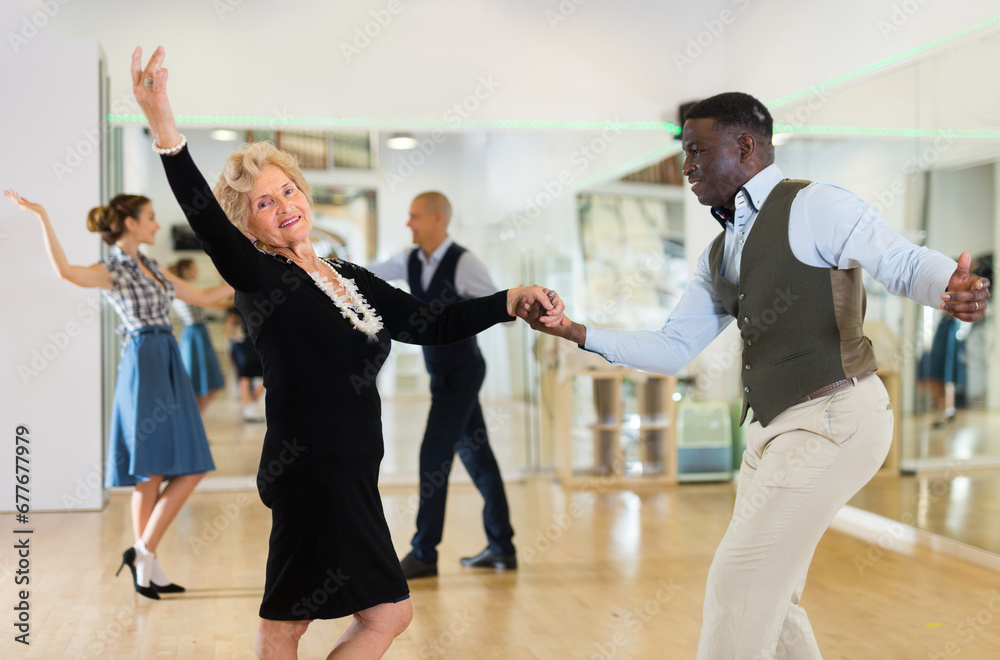 Fototapeta premium Lady learning to dance lindy hop with man in dance school