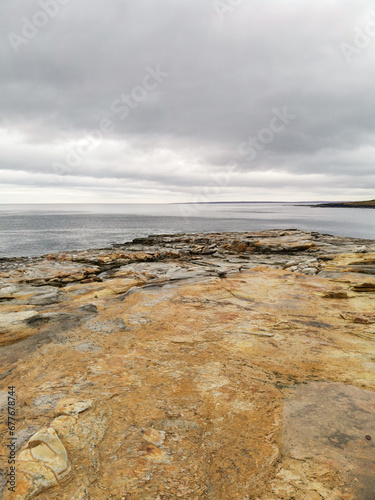 The shore of red stones next to the rocks are Two Brothers on the Fishing Peninsula. The picturesque shore of the harsh Barents Sea. The North of Russia. The Kola Peninsula. The Arctic