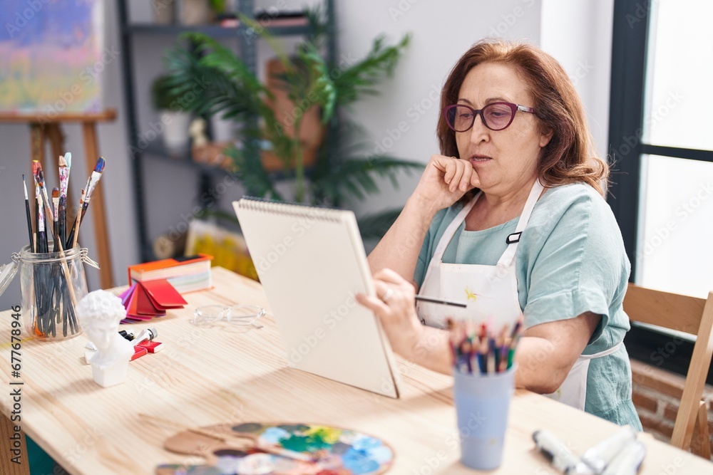 Senior woman artist drawing on notebook at art studio Senior woman artist drawing on notebook at art studio