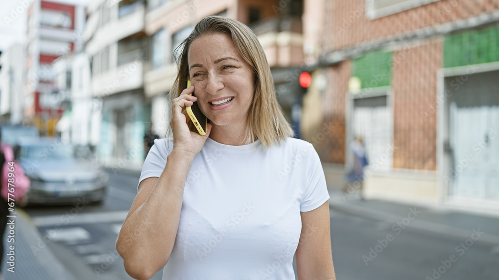 Young blonde woman speaking on the phone at street