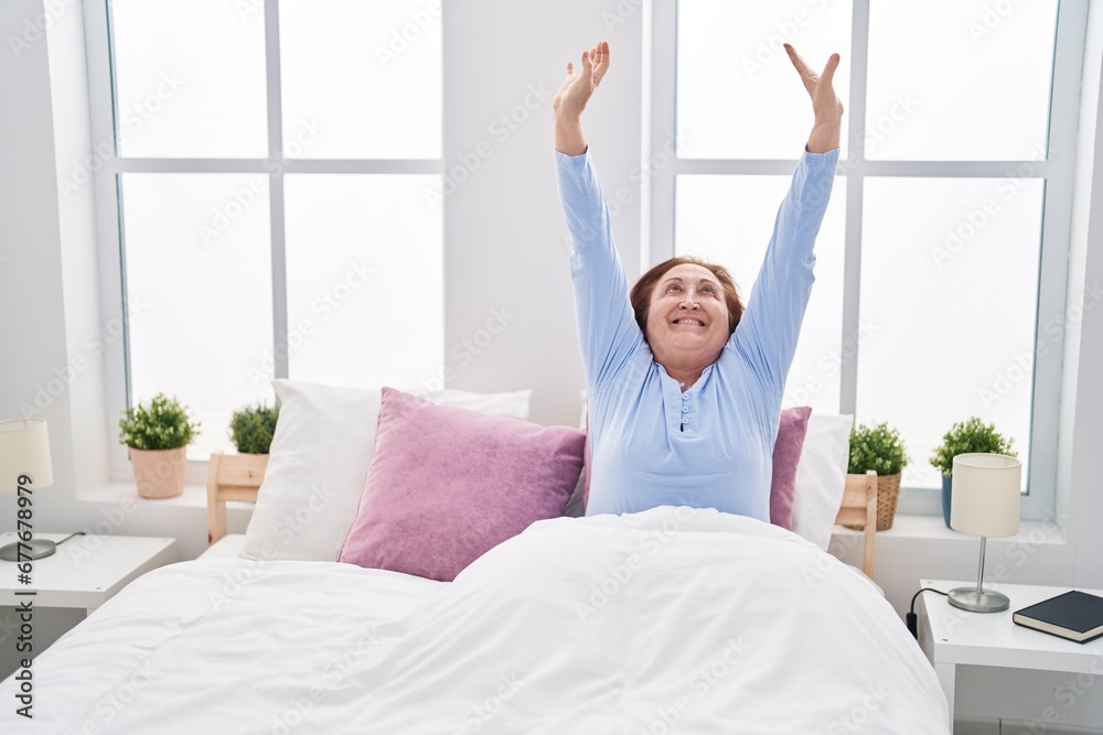 Senior woman waking up stretching arms at bedroom Senior woman waking up stretching arms at bedroom