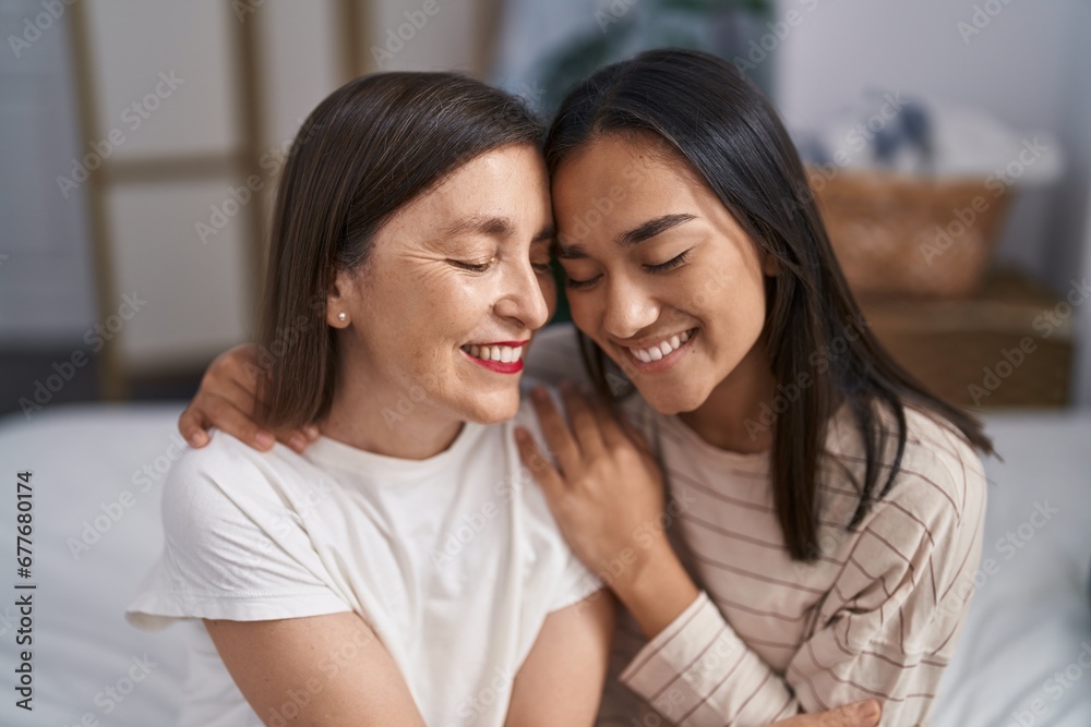Two women mother and daughter hugging each other sitting on bed at bedroom Two women mother and daughter hugging each other sitting on bed at bedroom