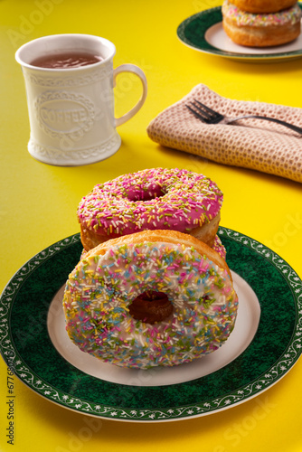 A plate of glazed doughnuts with sprinkles and a mug of coffee
