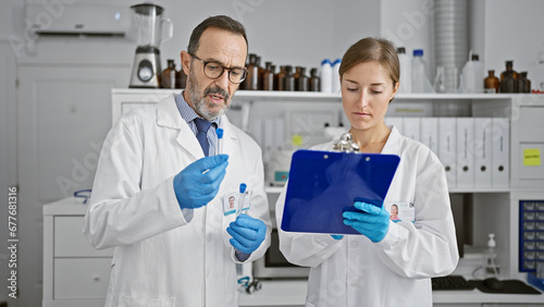 Two scientists holding test tube taking notes at laboratory