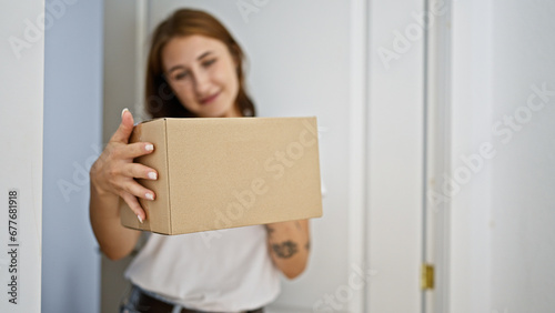 Young woman opening door holding package at home