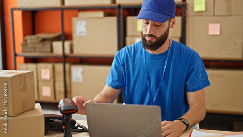 Young hispanic man ecommerce worker scanning packages at office