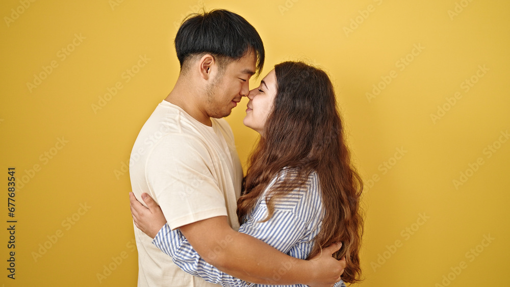 Man and woman couple hugging each other touching nose over isolated yellow background Man and woman couple hugging each other touching nose over isolated yellow background