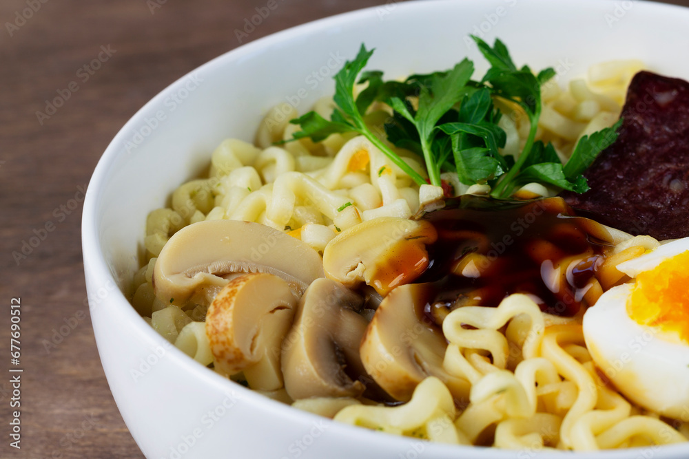 close-up of ramen noodles with chicken, boiled egg, mushrooms, spring onions and soy sauce. Korean soup. Traditional Asian cuisine. A white bowl of Korean soup with food sticks on the brown.