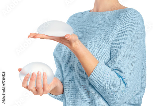 Woman holding and squeezing round implants on white background with clipping path. Mammoplasty and plastic surgery. photo