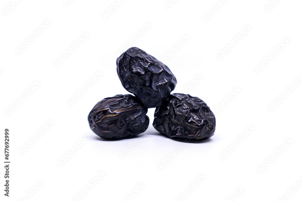 Creative layout made of three Ajwa dates fruits isolated on a white background. Ramadan Arabic food concept. Ajwa is a palm date that is widely grown in Medina and is good for health. Creative layout made of three Ajwa dates fruits isolated on a white background. Ramadan Arabic food concept. Ajwa is a palm date that is widely grown in Medina and is good for health.