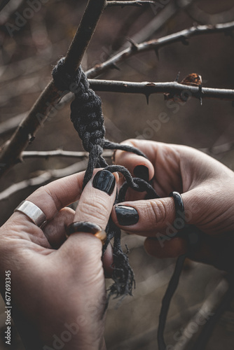 Female hands weaving a macrame braid on a tree branch