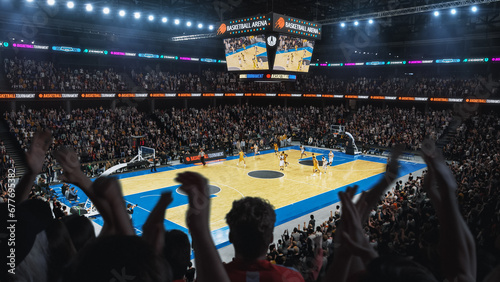 High Angle Establishing Wide Shot of a Whole Arena of Spectators Watching a Basketball Championship Game. Teams Play, Crowds of Fans Raise Hands and Cheer. Sports Channel Live Television Broadcast photo