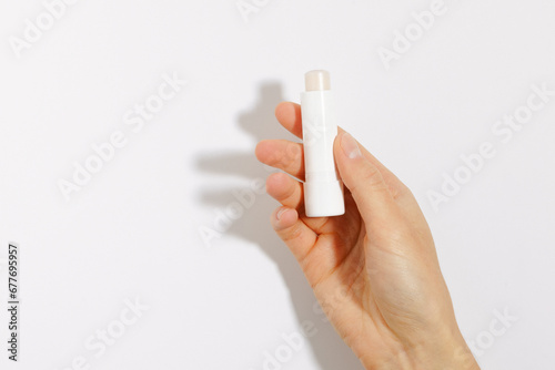 Female hand holding clear protective lip balm on white isolated background. Mockup for your design. The concept of decorative cosmetics for health and beauty photo