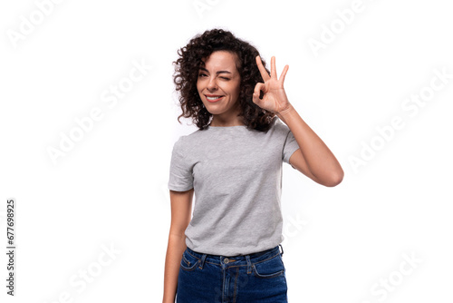 young smiling pretty brunette curly lady in a gray basic t-shirt on a white background with copy space