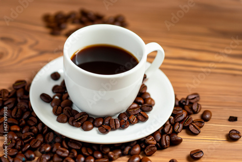 Cup of coffee and coffee beans on a wooden table.