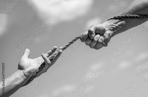 Rope, cord. Hand holding a rope, climbing rope, strength and determination. Rescue, help, helping gesture or hands. Black and white photo