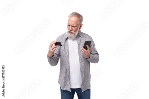 a handsome grandfather with a white beard and mustache, dressed in a striped shirt over a T-shirt, masters online payments using a smartphone and a plastic card