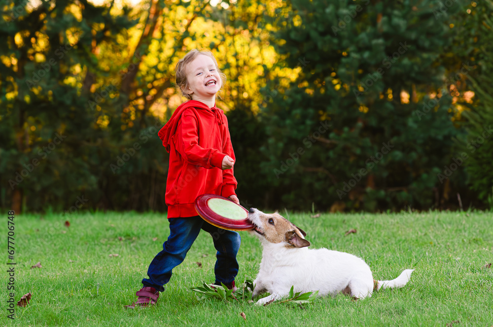 Happy little girl playing flying disk with her pet dog Happy little girl playing flying disk with her pet dog