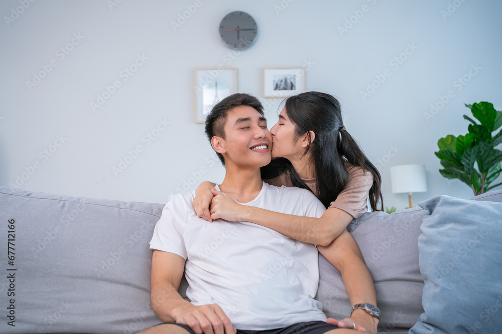 Obraz premium Happy relaxed young family couple homeowners or renters lying on big cozy sofa, enjoying carefree leisure weekend time, celebrating moving into new contemporary apartment, tenancy concept.