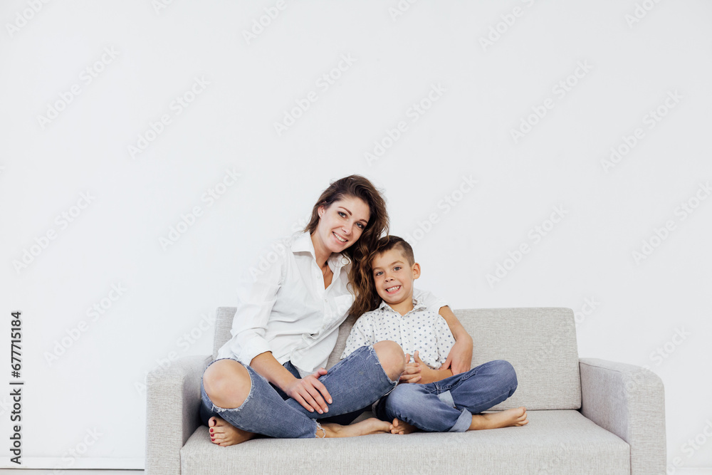 mother and son sitting on the couch in a white room mother and son sitting on the couch in a white room