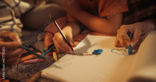 Close Up On Hands Of Happy Korean Family Drawing Together in Notebook With Pens And Pencils. Supportive Mother And Father Having Fun With Their Child At Home. Learning To Paint, Color And Write.
