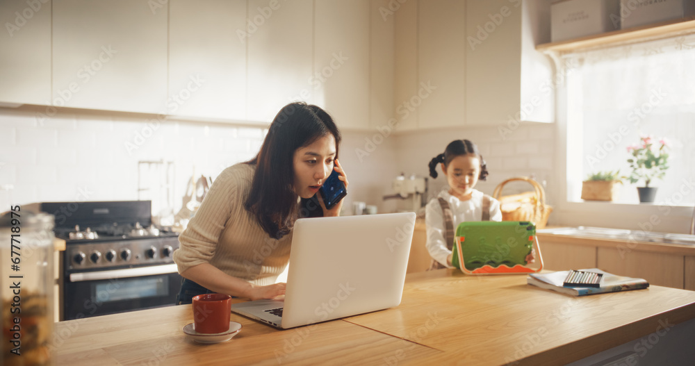 Portrait of Korean Mother Using Laptop and Smartphone To Work from Home While her Little Daughter is Using Digital Tablet. Productive Effective Businesswoman Doing Home Office Work and Being Super Mom Portrait of Korean Mother Using Laptop and Smartphone To Work from Home While her Little Daughter is Using Digital Tablet. Productive Effective Businesswoman Doing Home Office Work and Being Super Mom