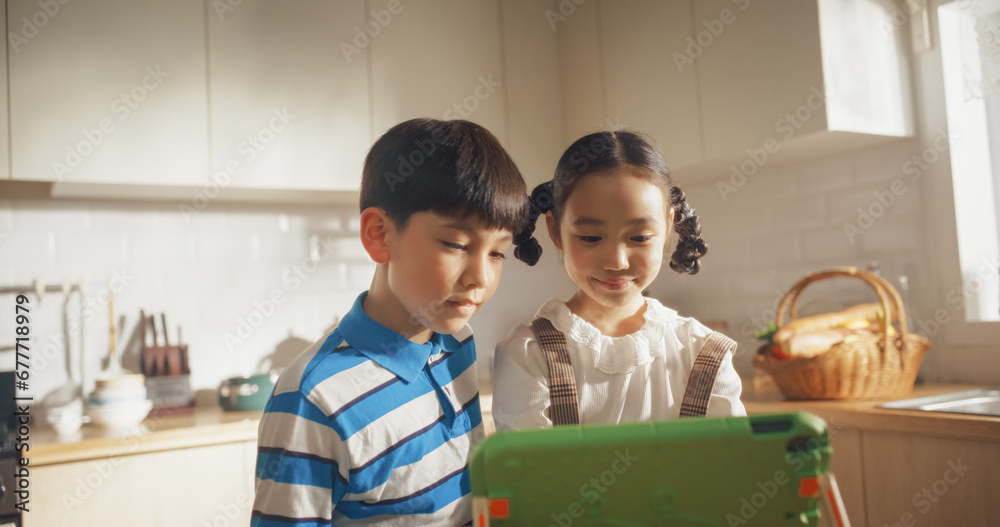 Portrait of Two Korean Kids Using a Digital Tablet During Weekend in The Kitchen. Two Cute Asian Siblings Watching Educational Content Online, Sharing the Gadget, and Enjoying Their Time Portrait of Two Korean Kids Using a Digital Tablet During Weekend in The Kitchen. Two Cute Asian Siblings Watching Educational Content Online, Sharing the Gadget, and Enjoying Their Time