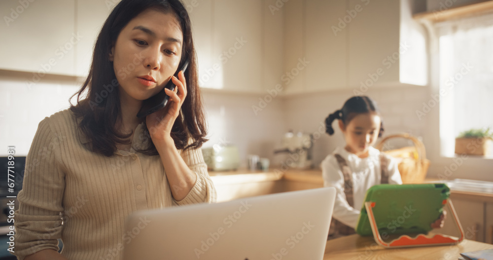 Portrait of Korean Mother Using Laptop and Smartphone To Work from Home While her Little Daughter is Using Digital Tablet. Productive Effective Businesswoman Doing Home Office Work and Being Super Mom Portrait of Korean Mother Using Laptop and Smartphone To Work from Home While her Little Daughter is Using Digital Tablet. Productive Effective Businesswoman Doing Home Office Work and Being Super Mom