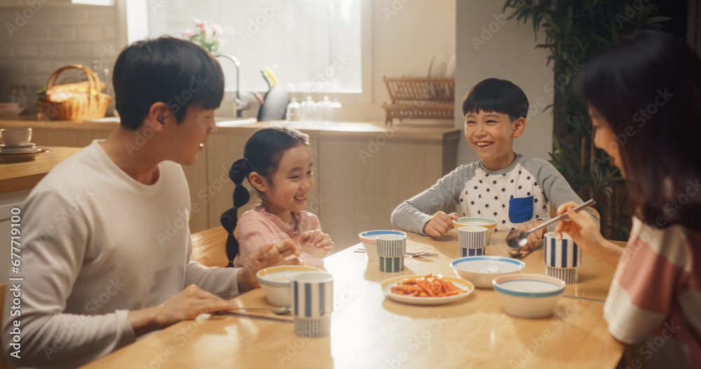 Happy Korean Family Members Enjoying Delicious Food Together. Young Parents and Their Two Children Eating Traditional Dishes at Home While Sitting at Their Kitchen Table Happy Korean Family Members Enjoying Delicious Food Together. Young Parents and Their Two Children Eating Traditional Dishes at Home While Sitting at Their Kitchen Table