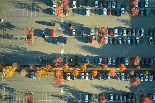 Aerial view of many colorful cars parked on parking lot with lines and markings for parking places and directions. Place for vehicles in front of a strip mall plaza © bilanol