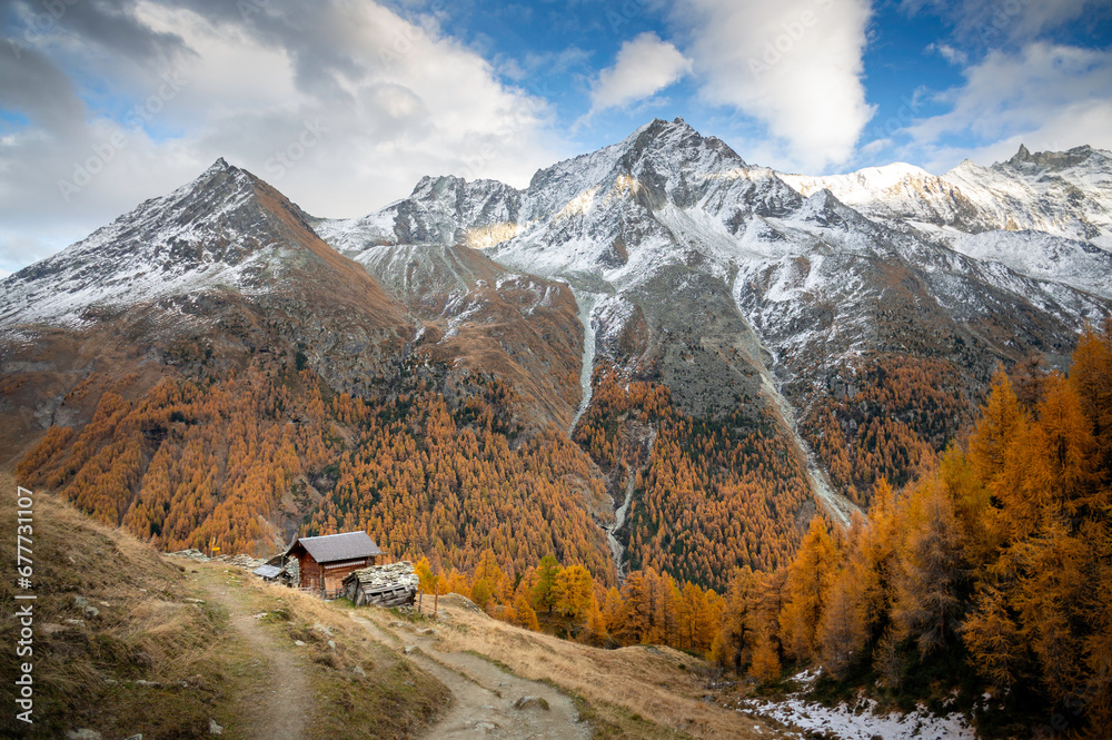 Alpine valley in autumn in Val d'Hérens in Switzerland with mountains, larch trees and small chalets Alpine valley in autumn in Val d'Hérens in Switzerland with mountains, larch trees and small chalets