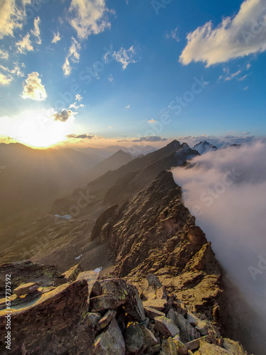 Obraz na płótnie Panoramic view of a mountain range in the Alps on the Italian-French border at sunset. Clouds rising hitting the natural barrier. Piedmont, Italy. w salonie